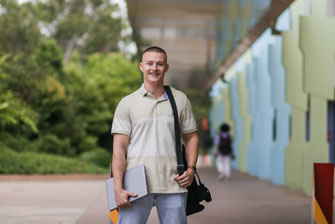 Student outside holding laptop