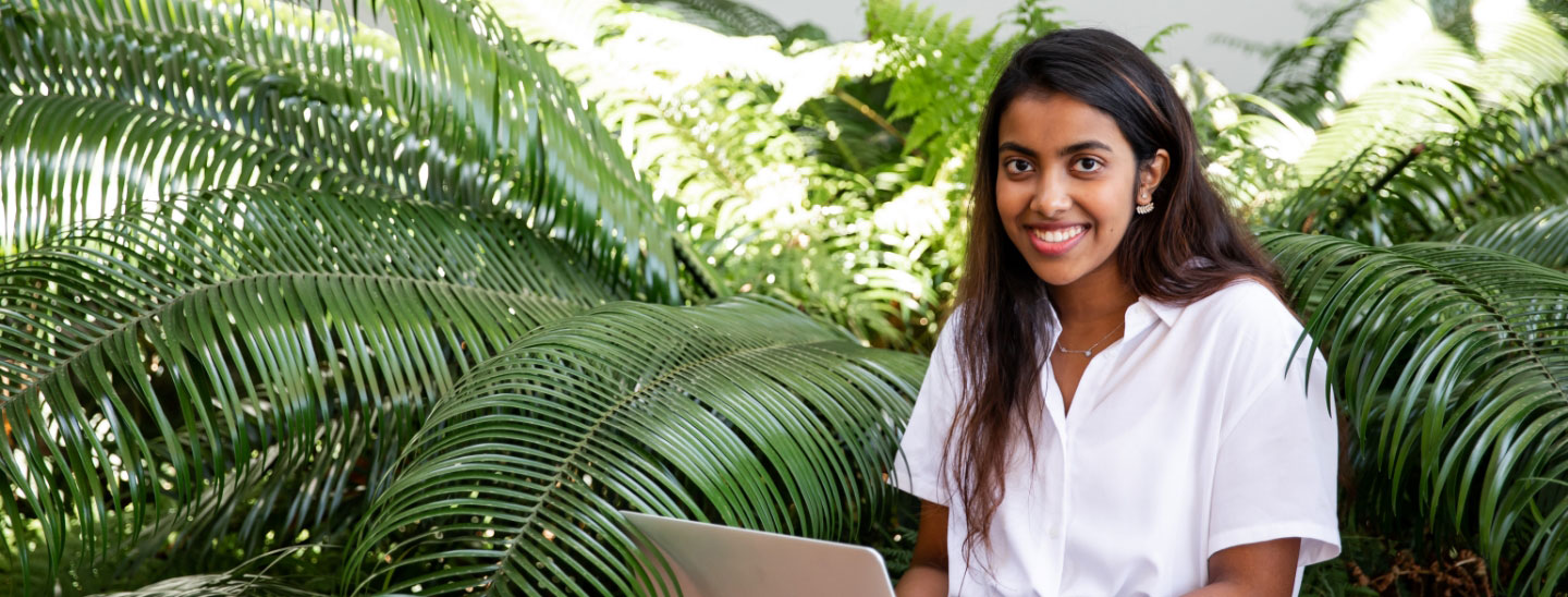 Student sitting outside laptop happy working