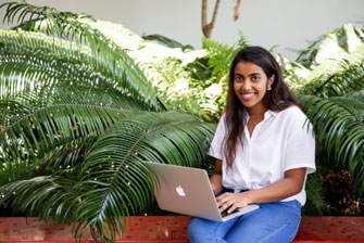 Student sitting outside laptop happy working